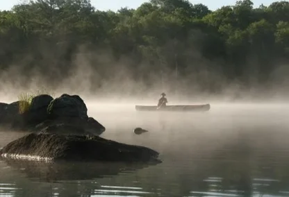 Person on a boat overtop of a misty lake in Haliburton Highlands
